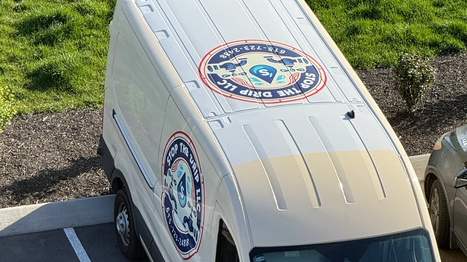 Plumbing service van parked beside a grassy slope