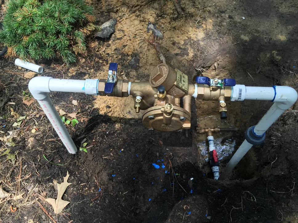 New brass backflow preventer with test cocks on irrigation pipe in a yard, backflow prevention