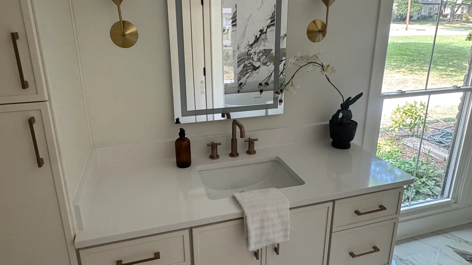 Bathroom vanity with a faucet and lighted mirror, plumbing