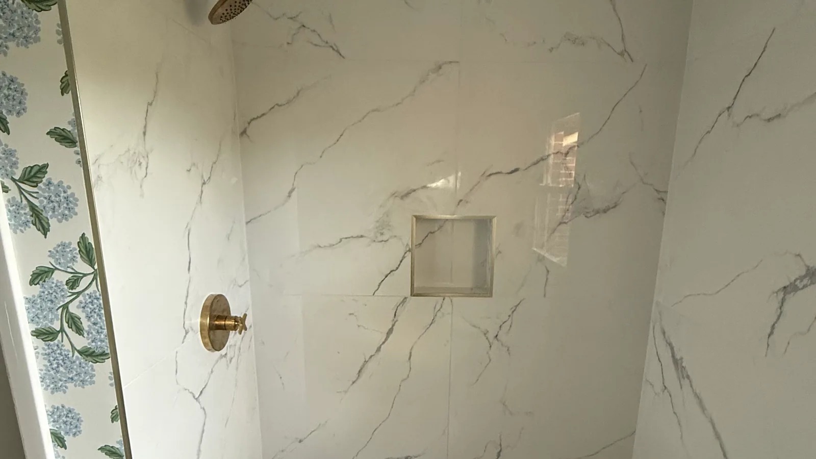Marble tile shower with a brass shower head, plumbing