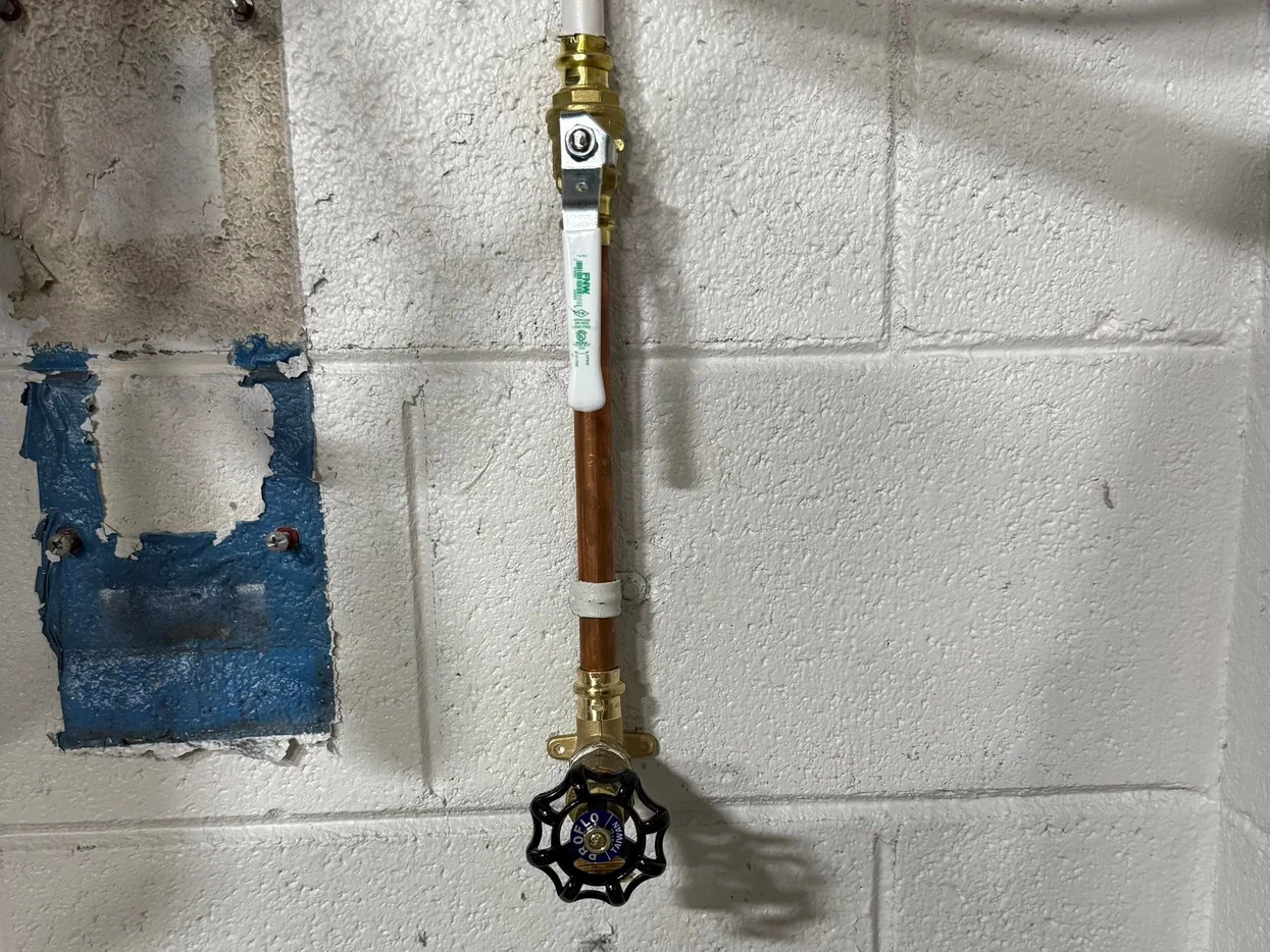 New spigot and shutoff valve on a copper line along a block wall, faucet repair