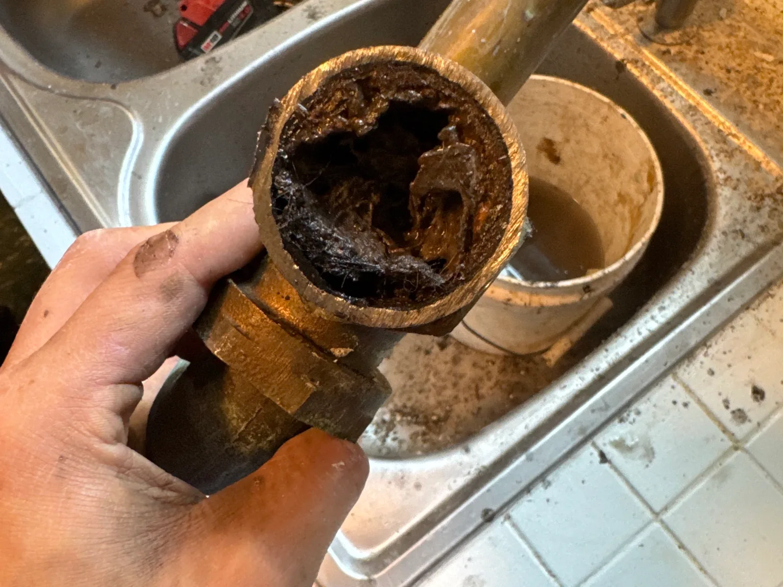 Clogged drain pipe pulled from a kitchen sink line, garbage disposal repair