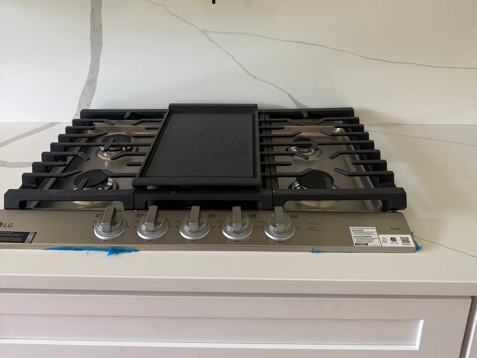 Gas cooktop with a griddle under a black pot filler, gas line installation