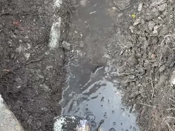 Water flowing through an exposed drain line in a trench, hydro jetting
