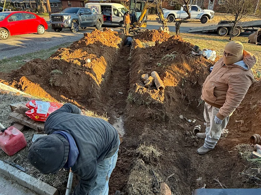 Crew digging a sewer line trench across a front yard, sewer line repair