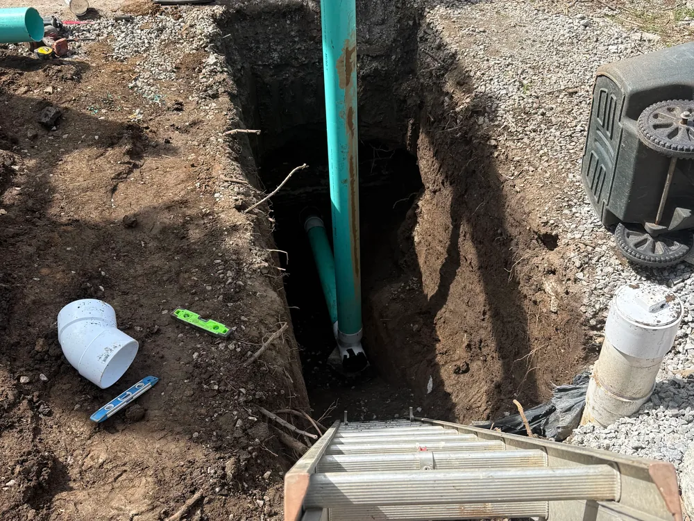 Green sewer pipe in a deep excavation with a ladder, sewer line repair