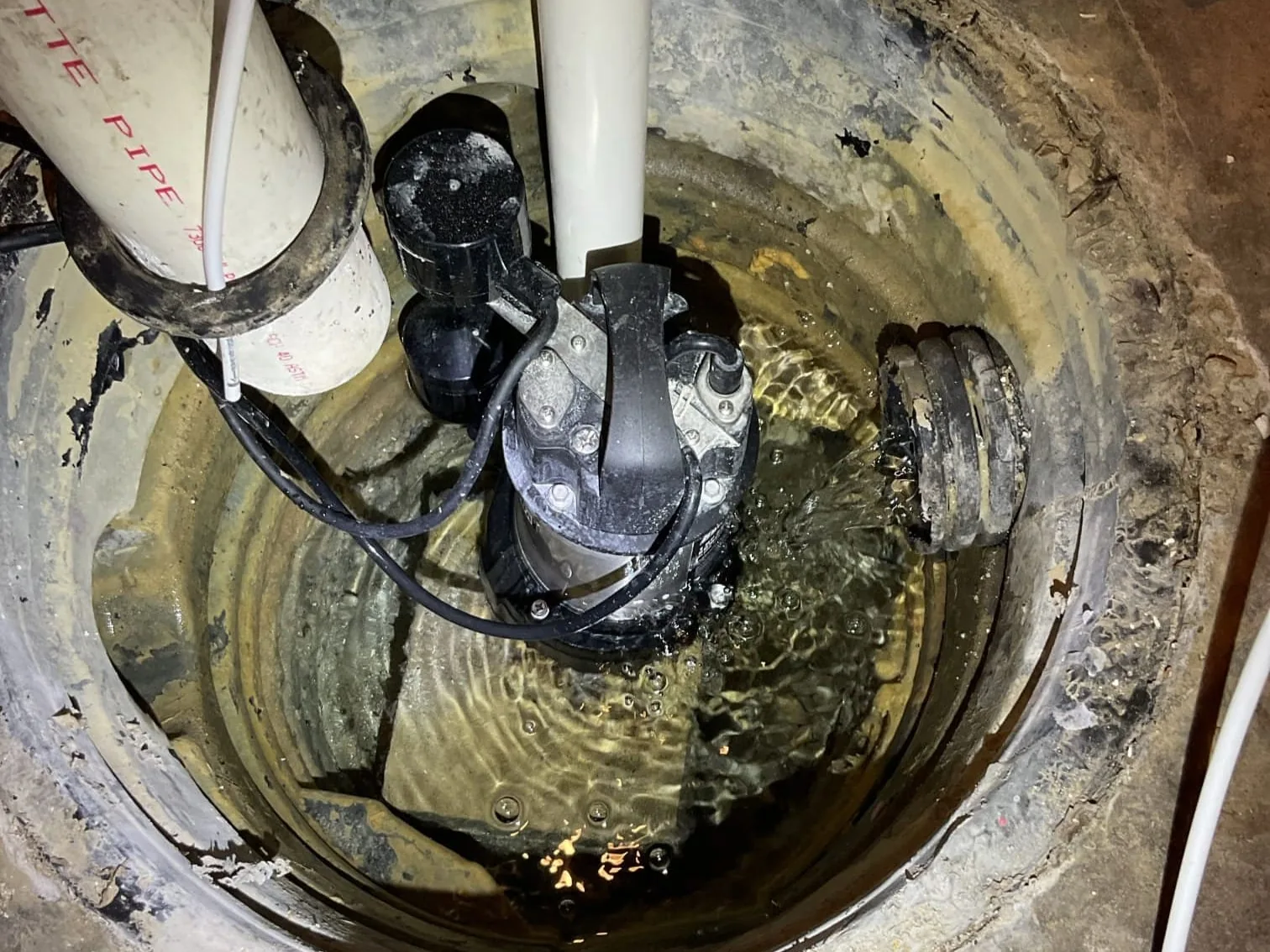 Submersible sump pump running in a basement pit, sump pump installation