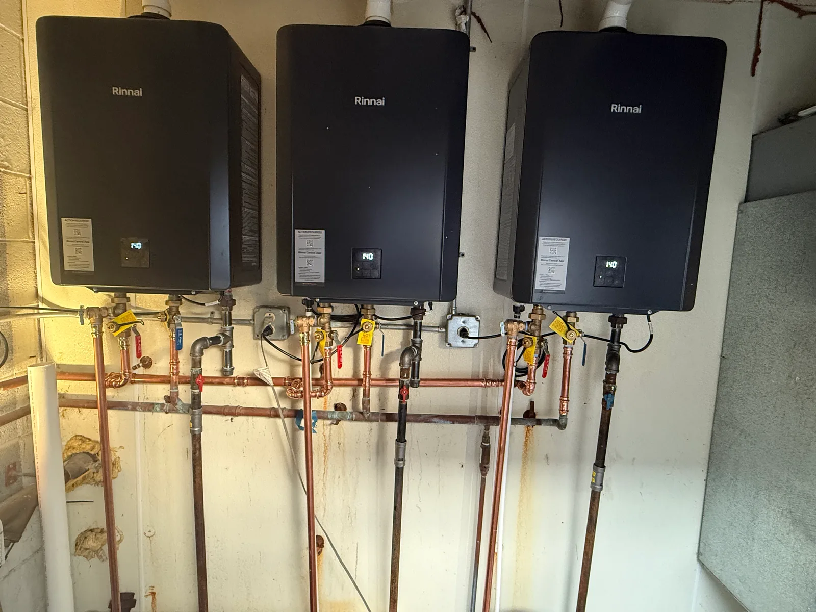 Three tankless water heaters with copper and gas piping, tankless water heater installation