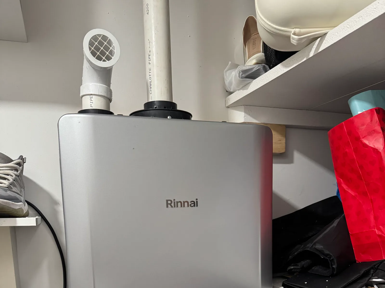 Tankless water heater with PVC vent pipes installed in a storage closet, water heater installation