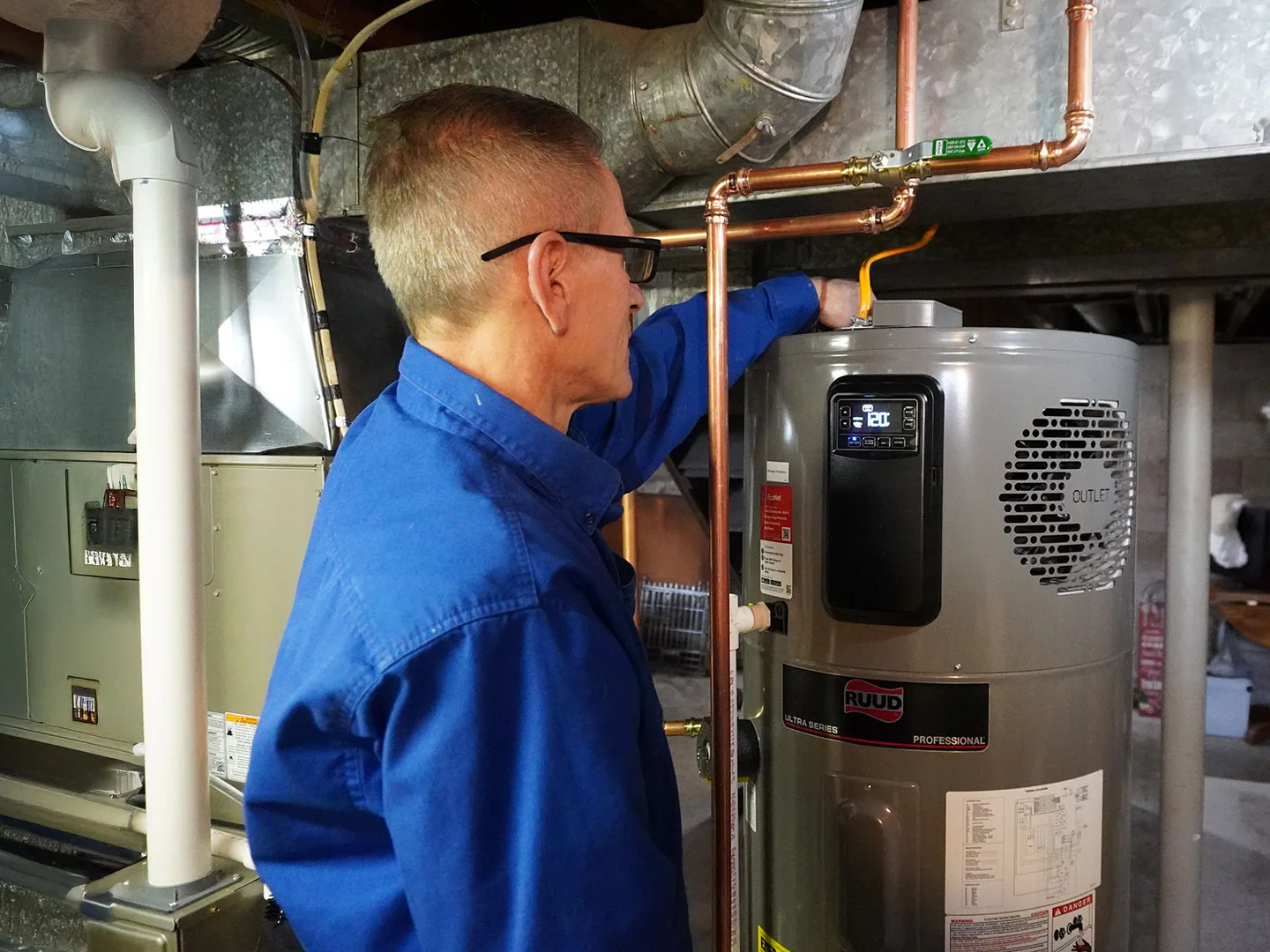 Technician connecting copper lines on a new tank water heater in a basement, water heater installation