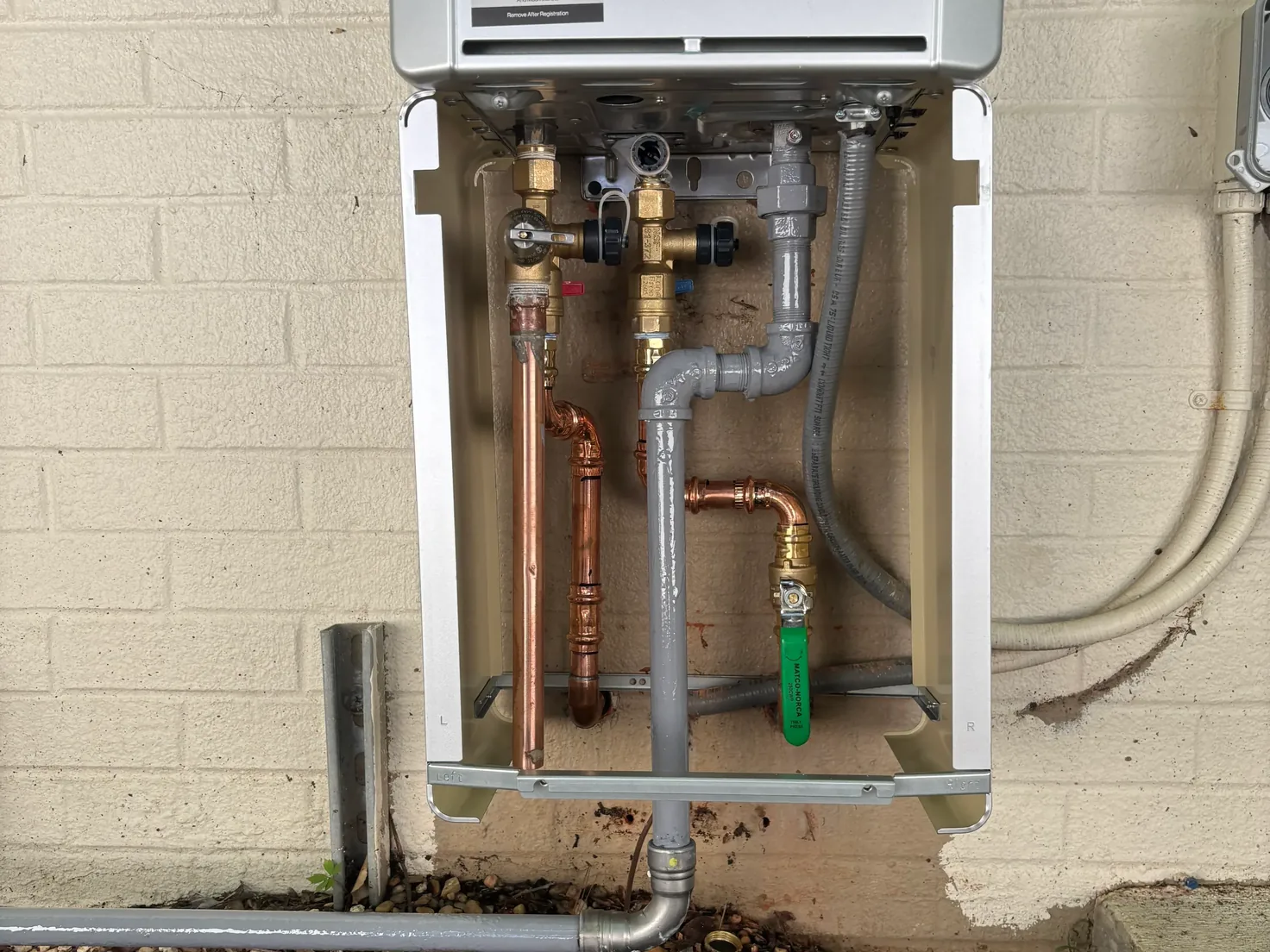 Tankless water heater on a brick wall with copper water lines and a gas line, water heater installation