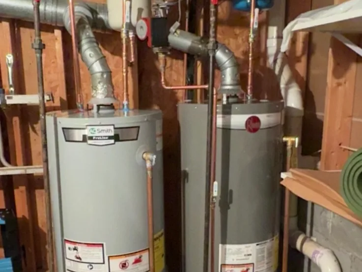 Two gas tank water heaters with flue pipes in a basement, water heater repair